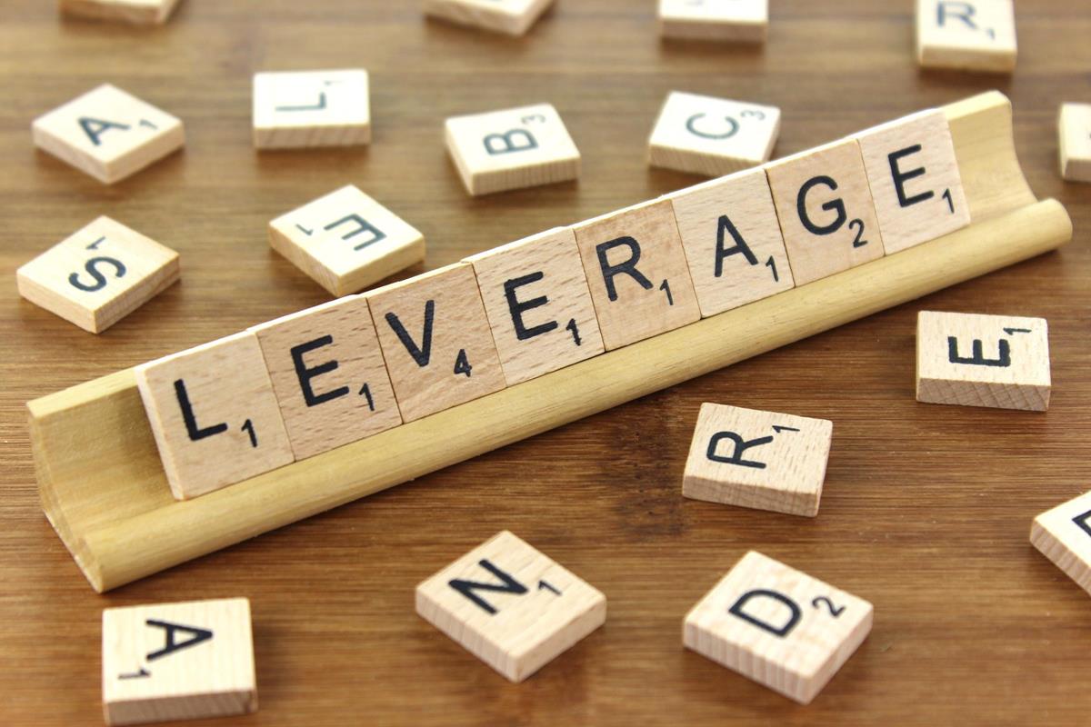 拼字游戏木块拼出的 LEVERAGE，周围散落着零乱的字母块